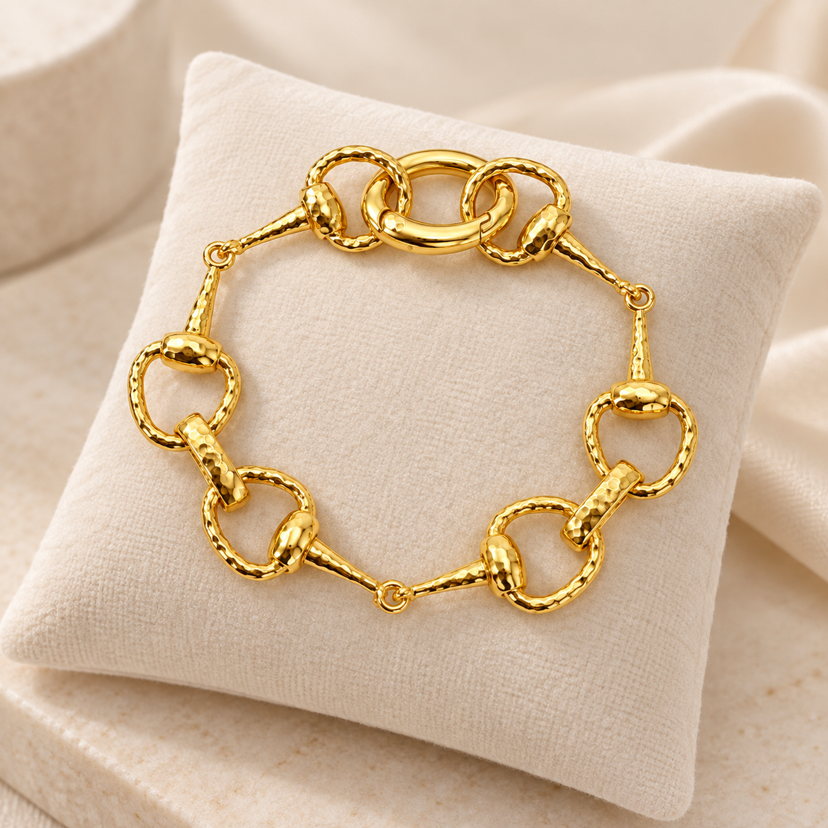 Golden equestrian horse bit link bracelet displayed on ivory jewelry cushion