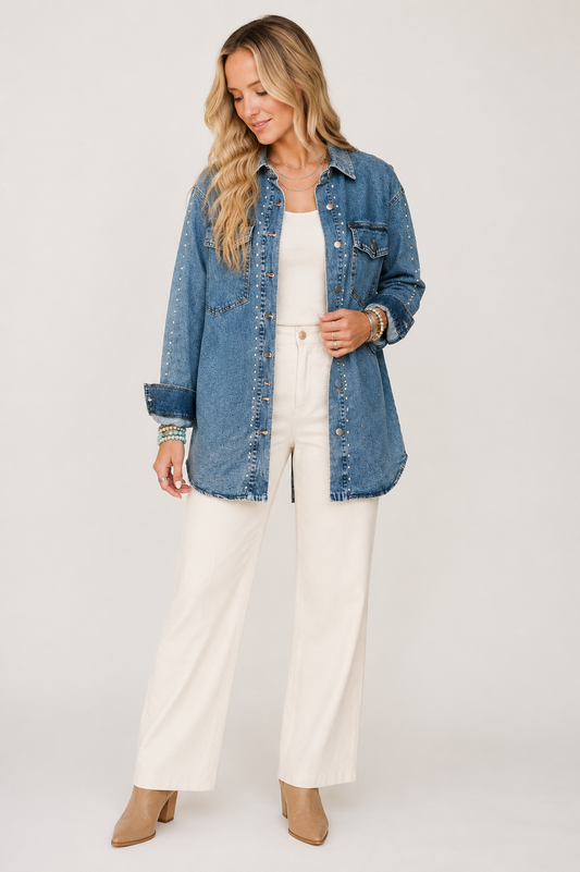 Blonde model wearing the Silver Spur sail-blue studded longline denim jacket with ivory trousers on a warm white background.