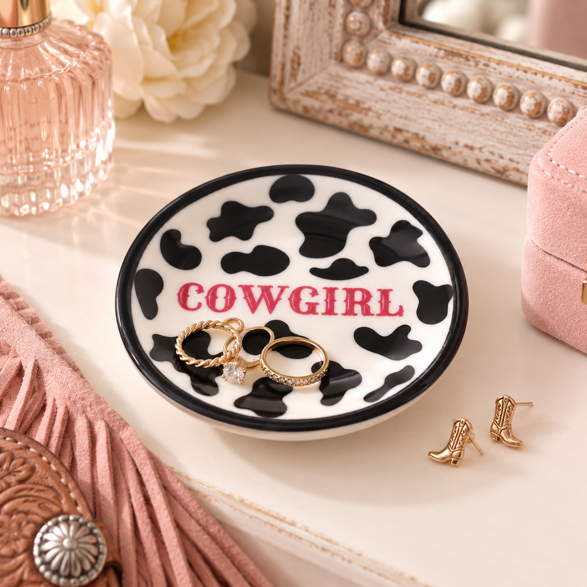 Cowprint Cowgirl ring dish styled on a western vanity with gold rings and earrings