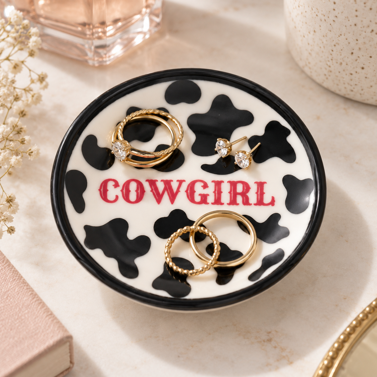Close-up of glossy Cowprint Cowgirl jewelry dish with black rim and pink western lettering
