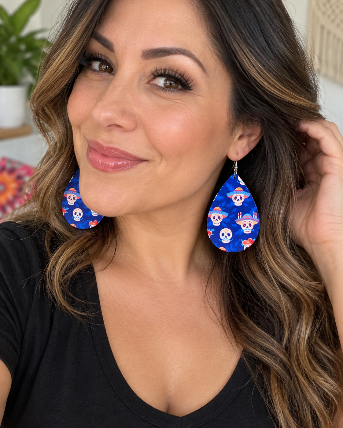 Lifestyle image of woman wearing blue sugar skull wood teardrop earrings with a simple black top