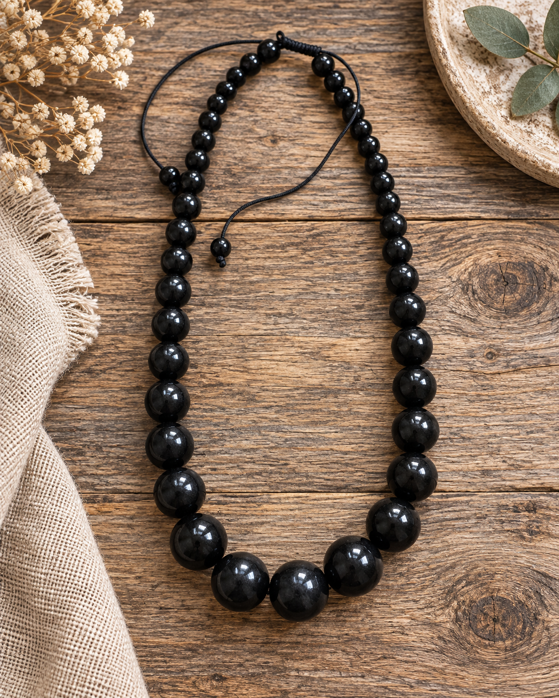 Midnight Muse black bead necklace styled on rustic wood with soft neutral accessories