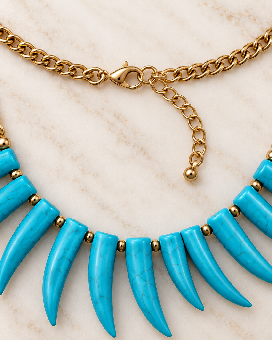 A close-up of a statement necklace featuring bright turquoise blue claw-shaped beads set with small gold spacer beads and connected by a gold chain.