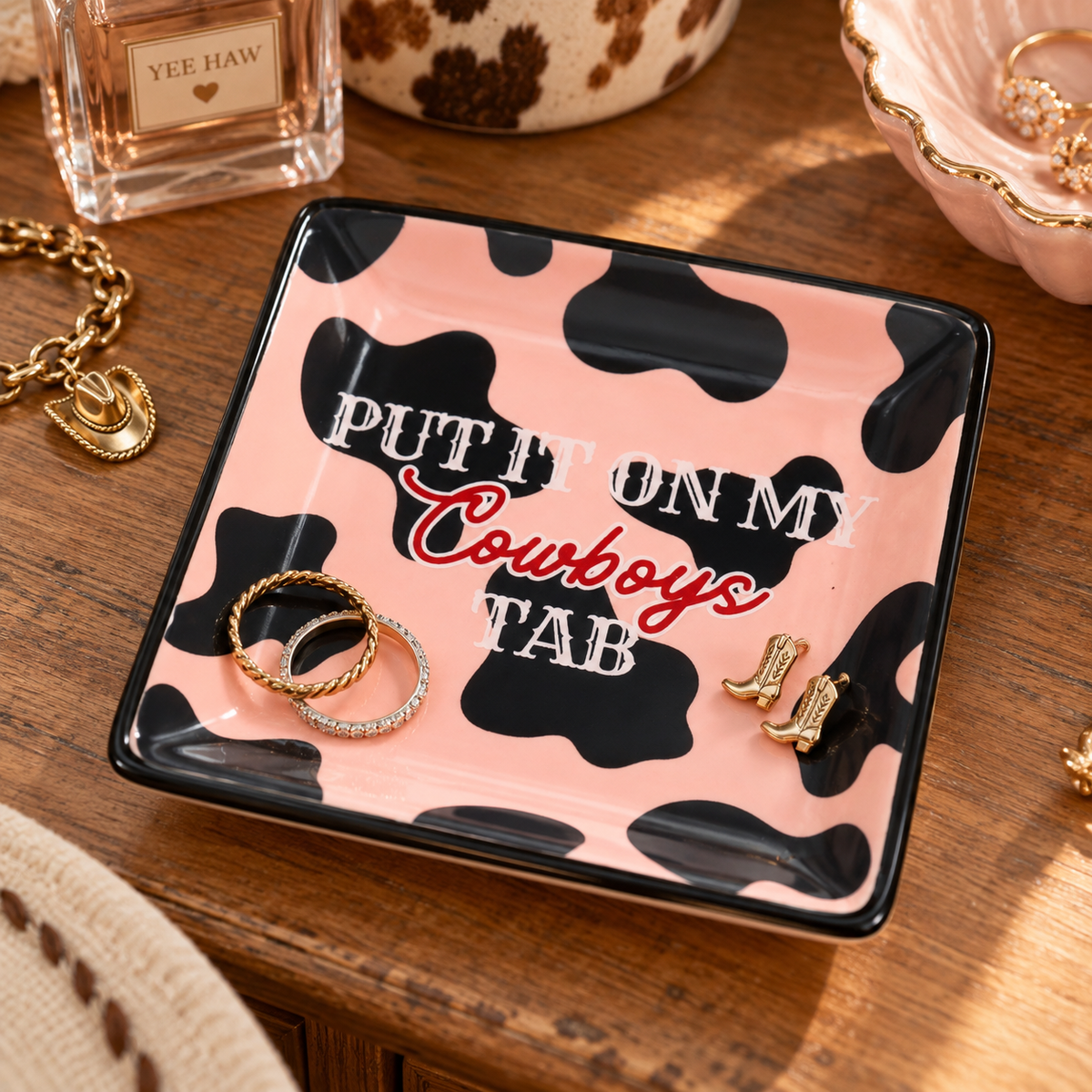 Western cowprint trinket tray styled with rings and jewelry on a wooden vanity