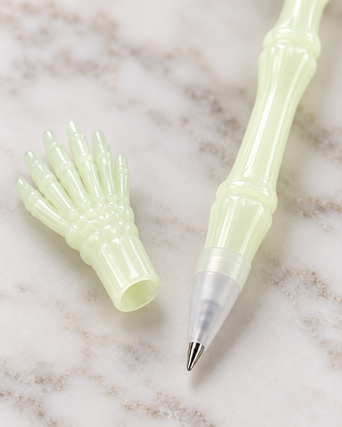 Close-up of skeleton hand pen tip and translucent bone-shaped barrel on a light surface