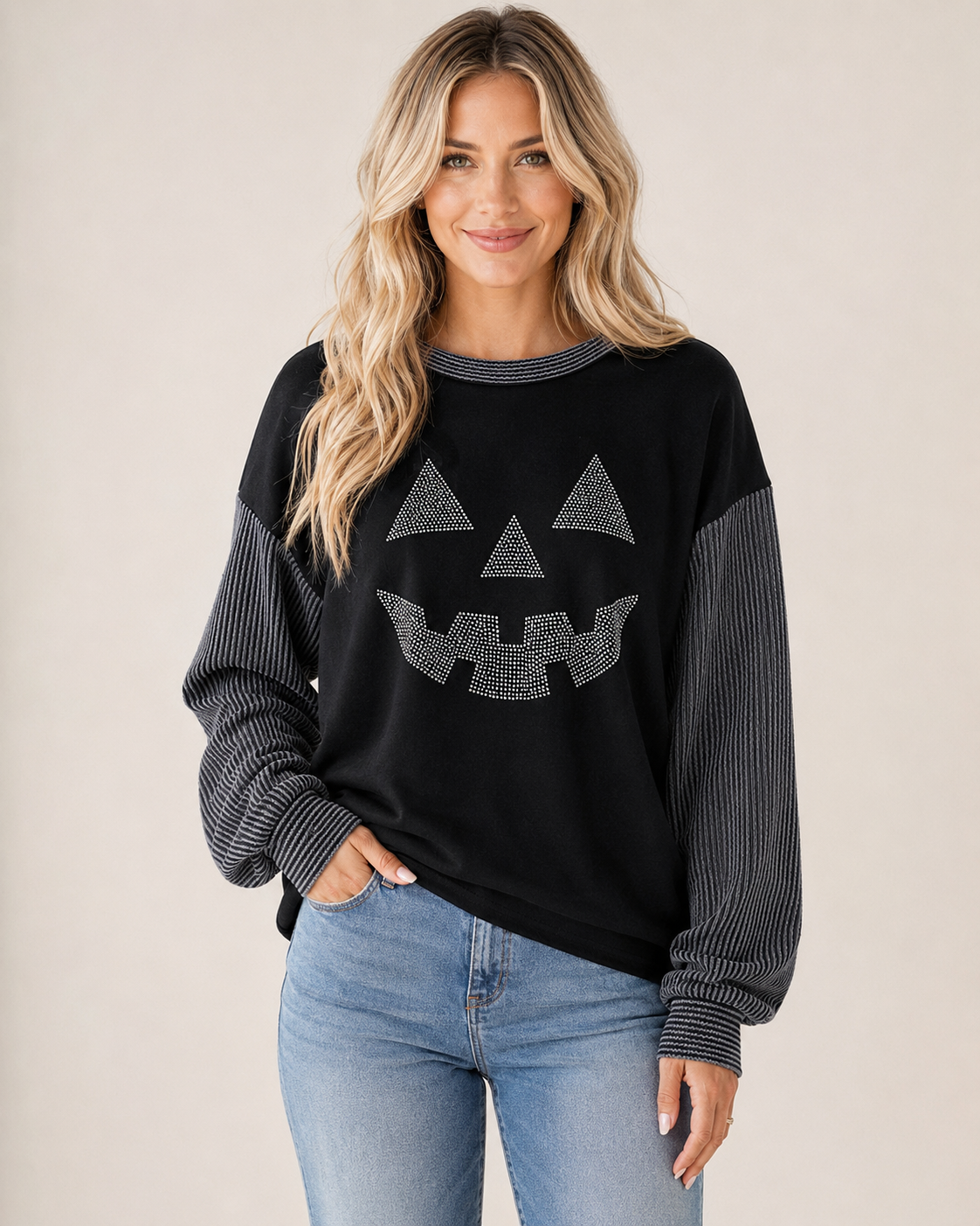 Black rhinestone jack-o’-lantern long-sleeve top with contrast gray ribbed sleeves styled with light-wash denim.