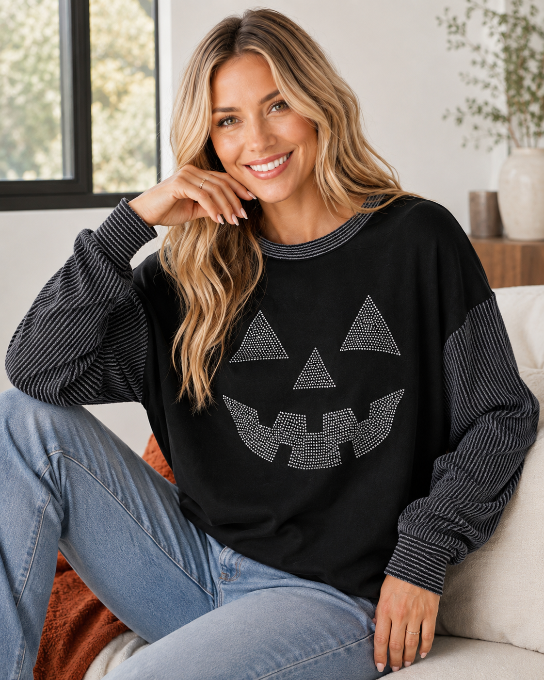 Blonde model wearing the Midnight Jack Rhinestone Top with light-wash jeans in a relaxed indoor fall lifestyle setting.