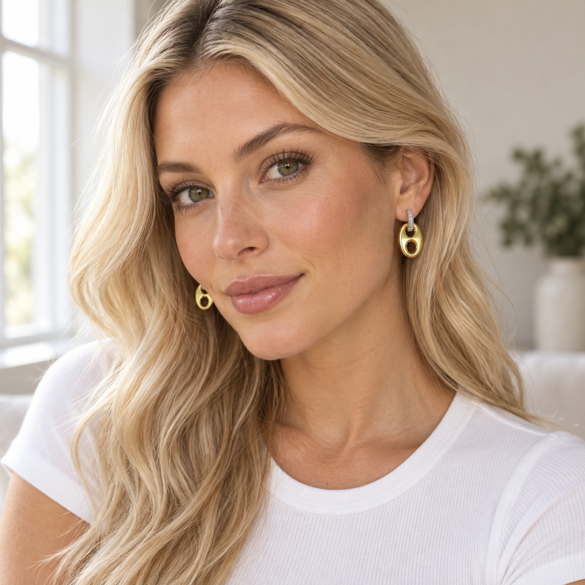 Woman wearing two-tone horse bit drop earrings with a white tee