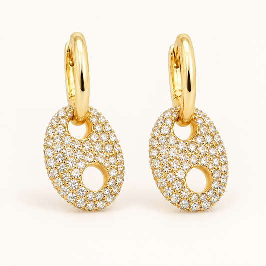 Arena Lights gold pavé horse bit huggie earrings on a warm-white background