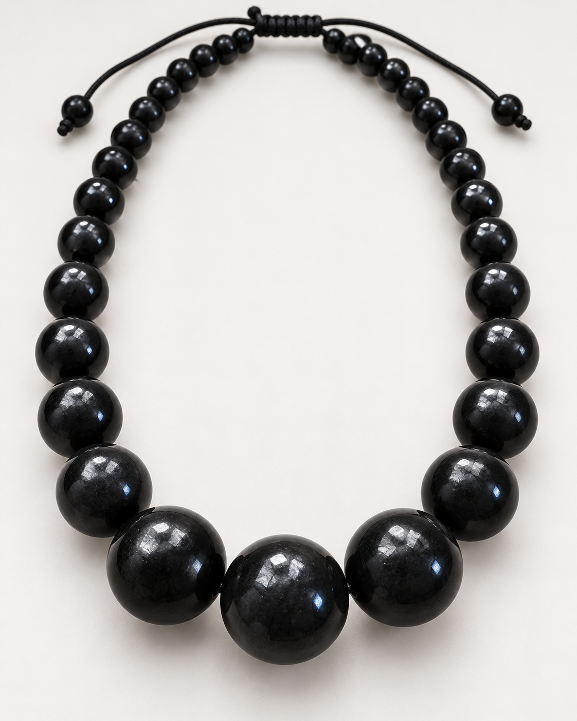 Close-up of glossy graduated black beads showing the larger center bead design