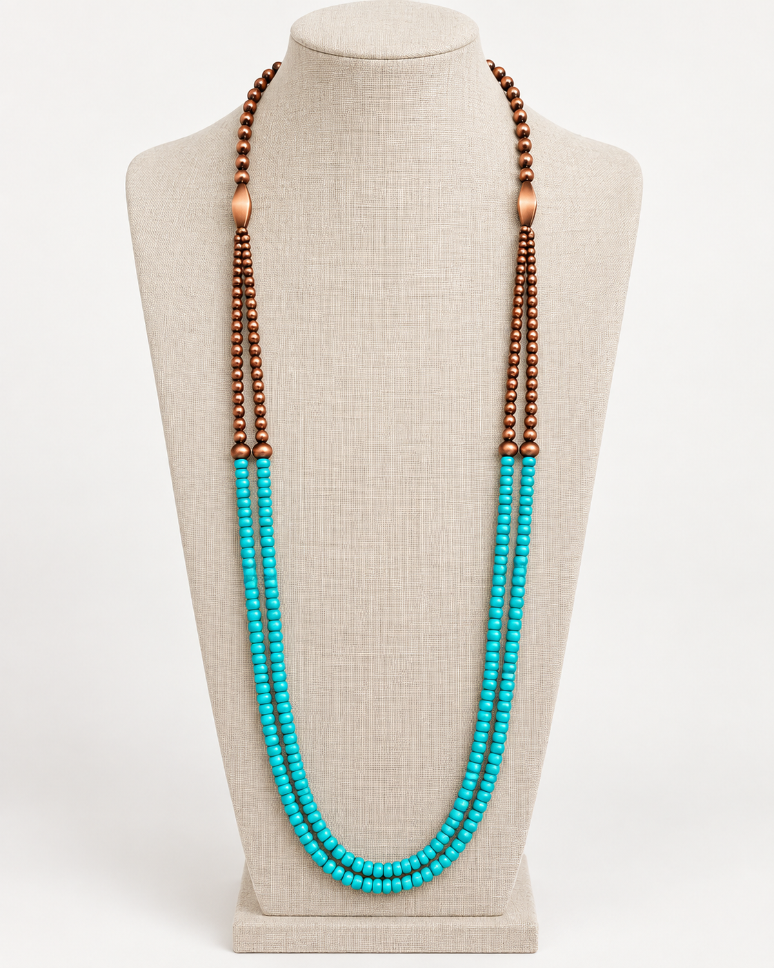 Long turquoise-colored and copper-tone double-strand necklace displayed on a neutral linen jewelry bust