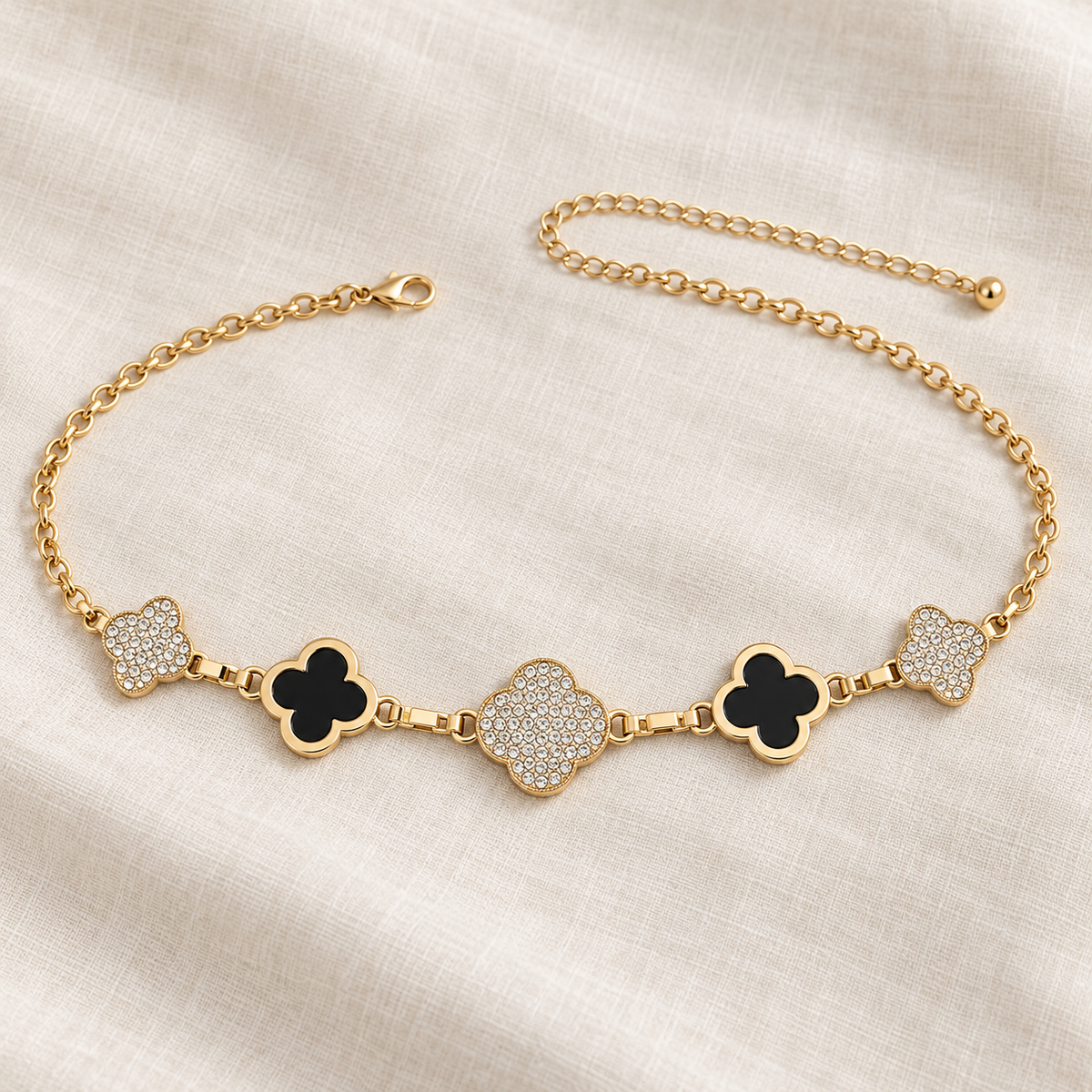 Gold-tone City Lights rhinestone quatrefoil chain belt displayed on soft ivory linen