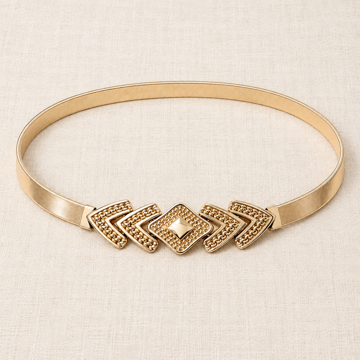 Gold-tone Desert Deco stretch metal waist belt displayed on soft ivory linen.