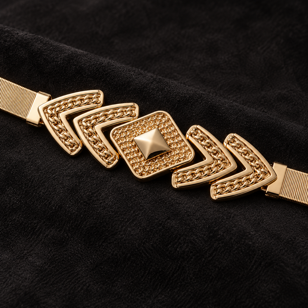Close-up of the gold-tone diamond and chevron belt centerpiece on black suede.