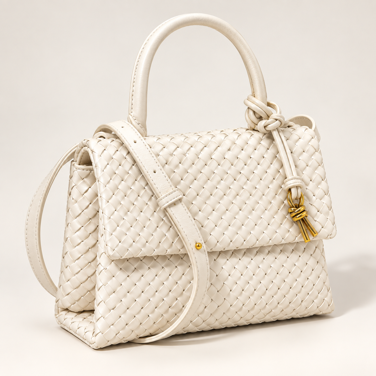 White Sutton woven handbag with structured top handle, adjustable crossbody strap and gold-tone knotted accent