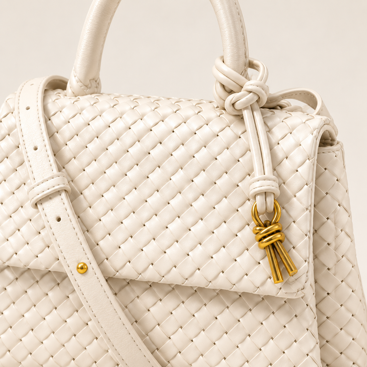 Close-up of white Sutton handbag showing detailed woven faux leather texture, knotted accent and gold-tone hardware