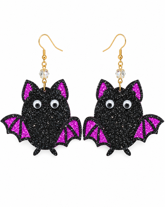 A pair of black glitter bat dangle earrings with bright pink glitter wings, gold-tone hooks, and clear rhinestone beads, shown on a plain white background.