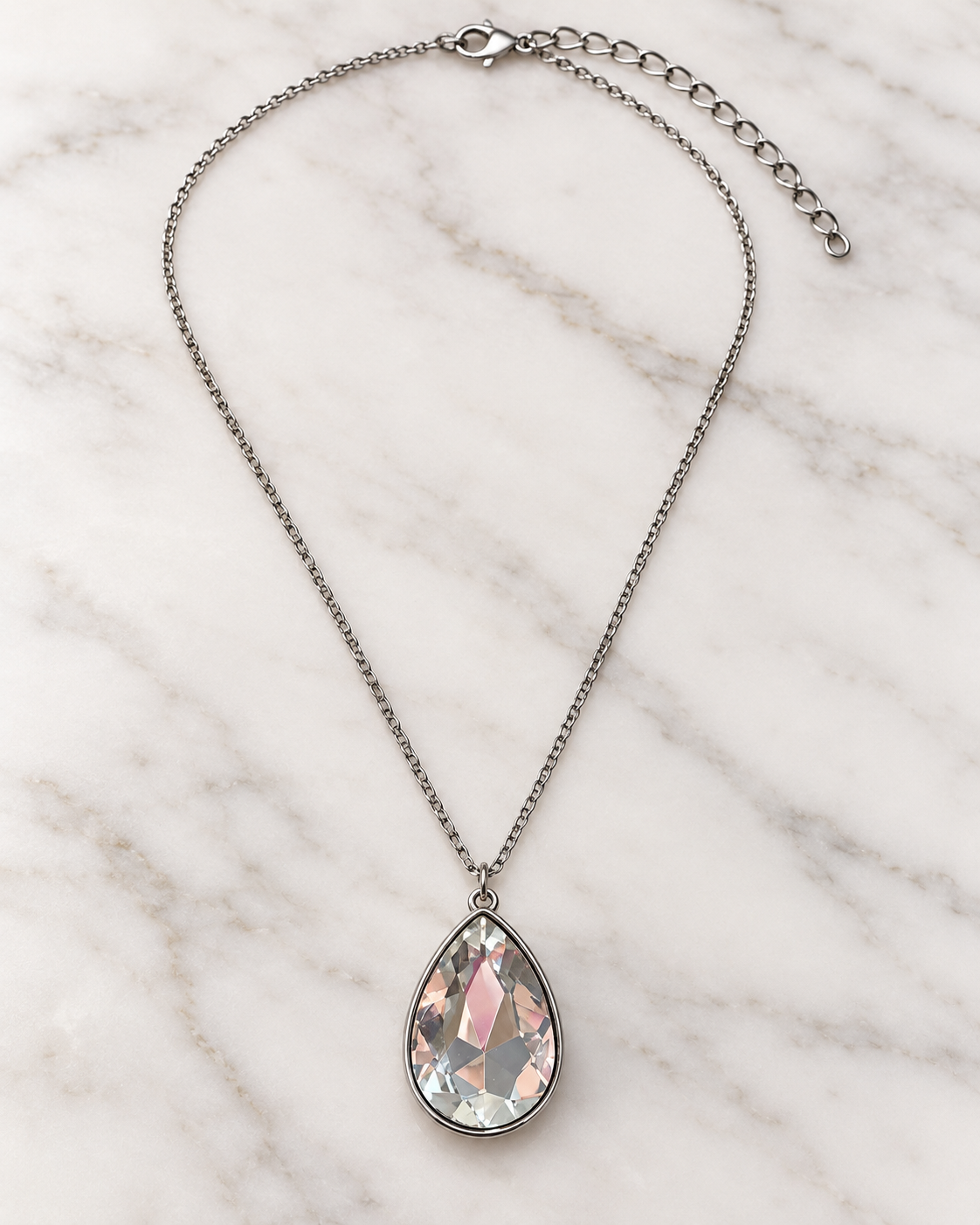 Afterglow teardrop pendant necklace styled on light marble with silver-tone chain and extender