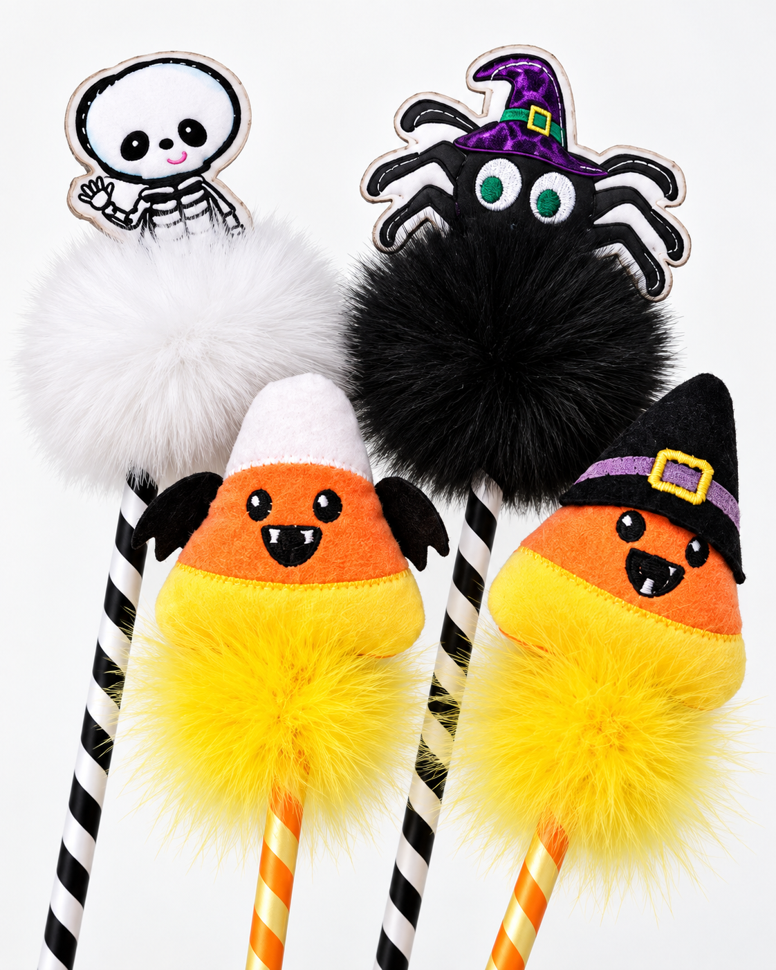 Three Halloween-themed novelty pens with fluffy pom-poms and striped handles, featuring a skeleton, a black spider, and two candy corn characters on a plain white background.