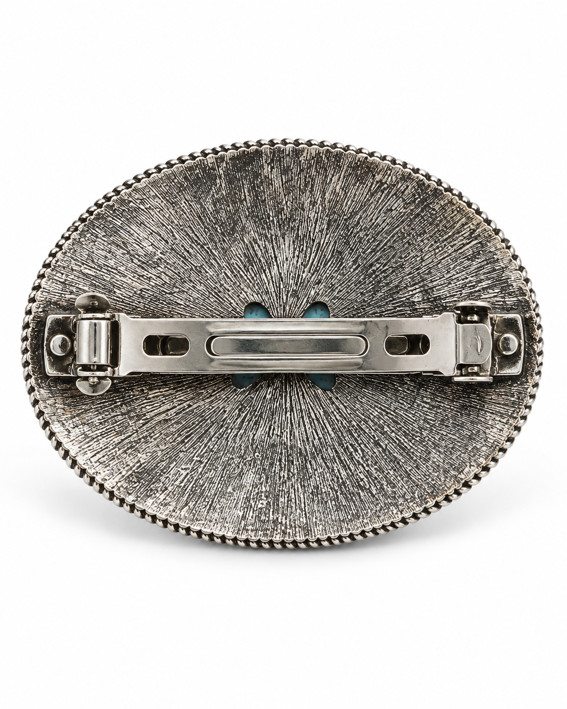 Silver oval brooch with a textured sunburst pattern and a beaded border, shown from the back with its metal pin clasp visible against a white background.