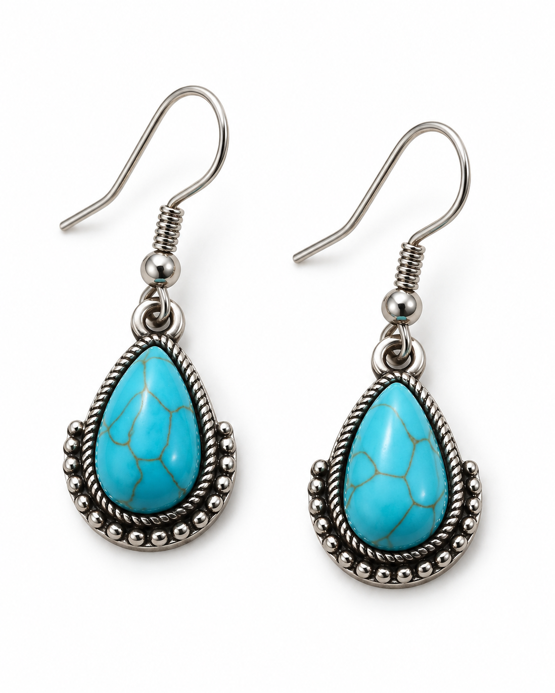 A pair of silver-toned drop earrings featuring teardrop-shaped turquoise stones with natural matrix lines, set in a braided silver bezel with beaded borders, on a plain white background.