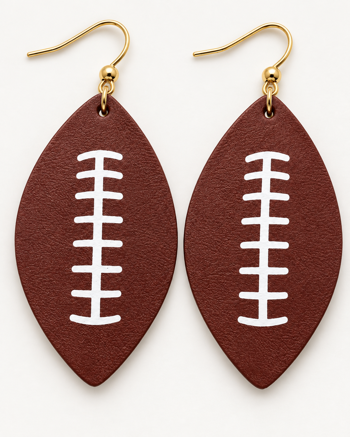 Close-up of football-shaped earrings showing textured brown surface and crisp white lace design
