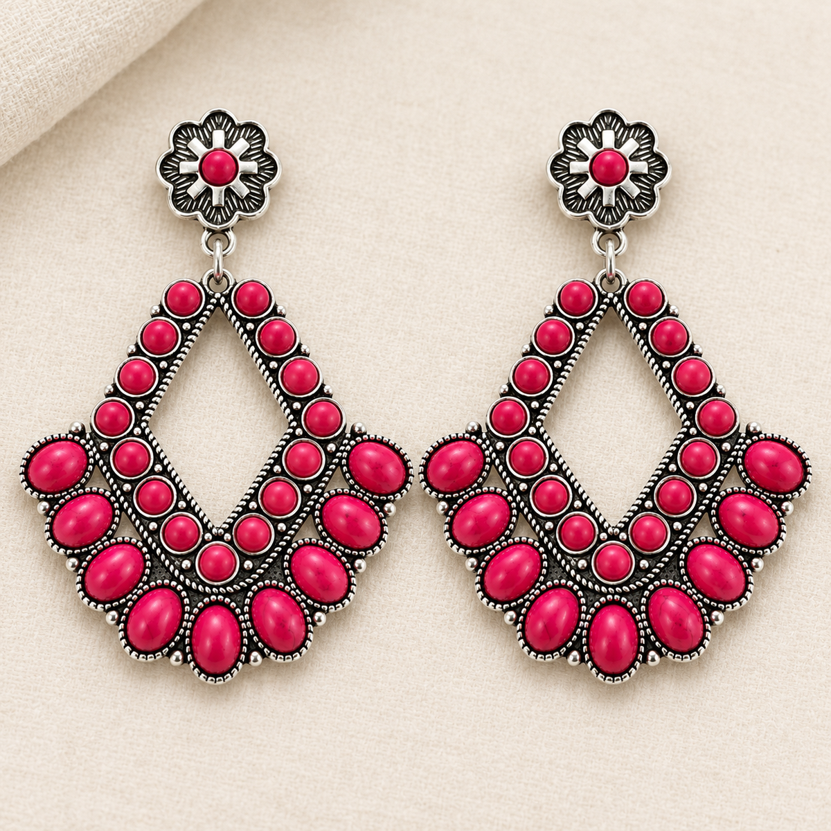 Rodeo Rose pink stone statement earrings displayed on soft neutral fabric