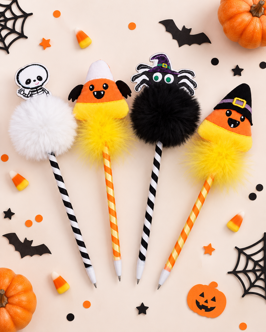 Four Halloween-themed decorative pencils arranged on a light beige background with candy corn, pumpkins, spiderwebs, and black stars. The pencils have fluffy pom-poms in white, orange-and-yellow, black, and orange-and-yellow, with black-and-white striped and orange-and-yellow striped handles.