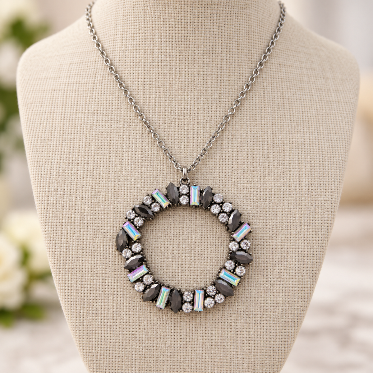 Crystal wreath pendant necklace displayed on a neutral linen jewelry bust with silver-tone chain