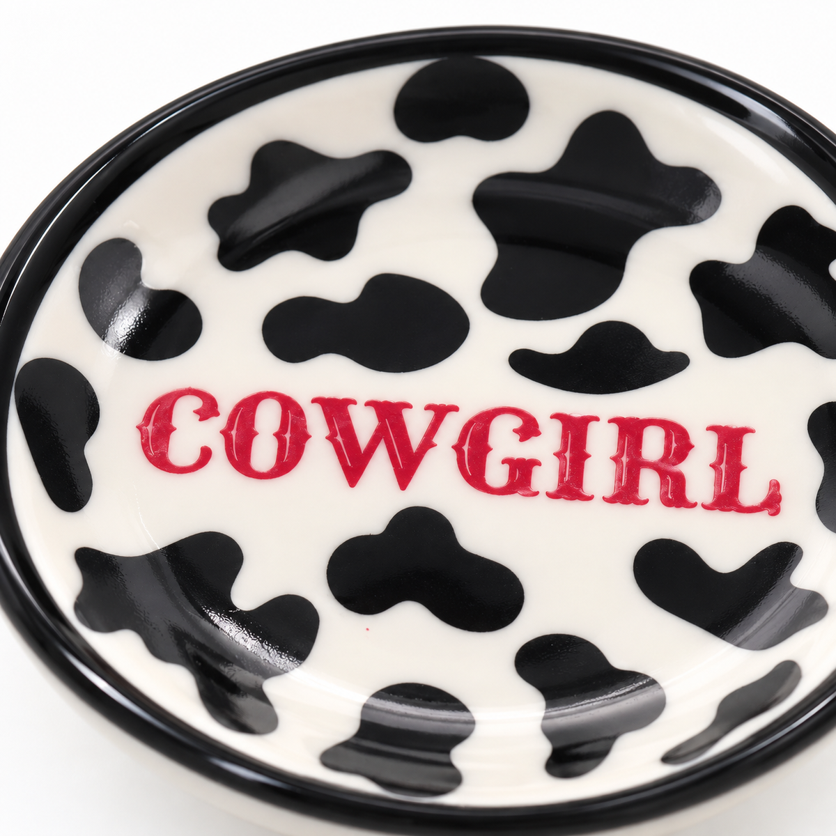 Cowprint Cowgirl trinket dish holding gold rings and stud earrings on a feminine vanity