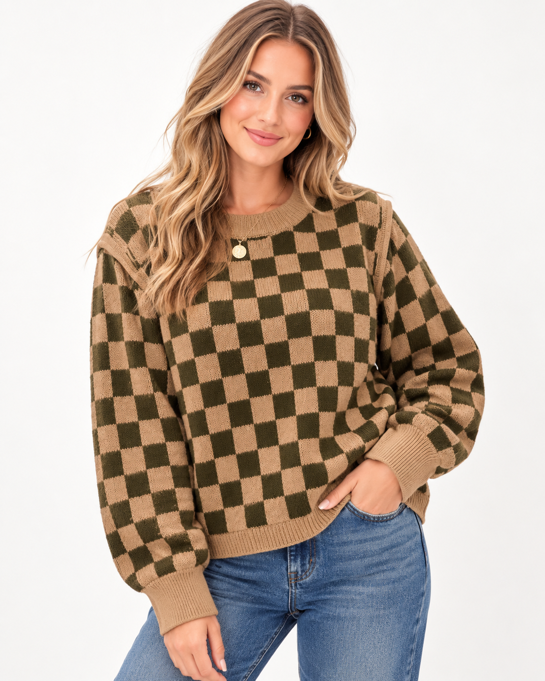 A woman wearing a brown and olive green checkered knit sweater with a single gold button, paired with blue jeans, against a plain white background.