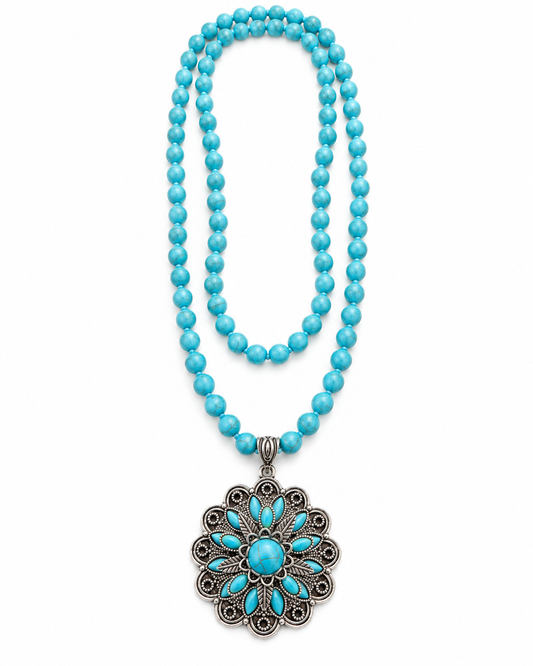 A turquoise beaded necklace with a large silver filigree pendant featuring a turquoise center, displayed on a clean white background.