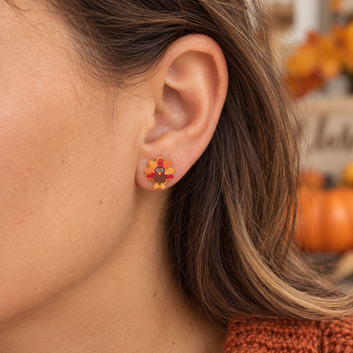 Woman wearing little turkey Thanksgiving stud earrings in a warm fall setting