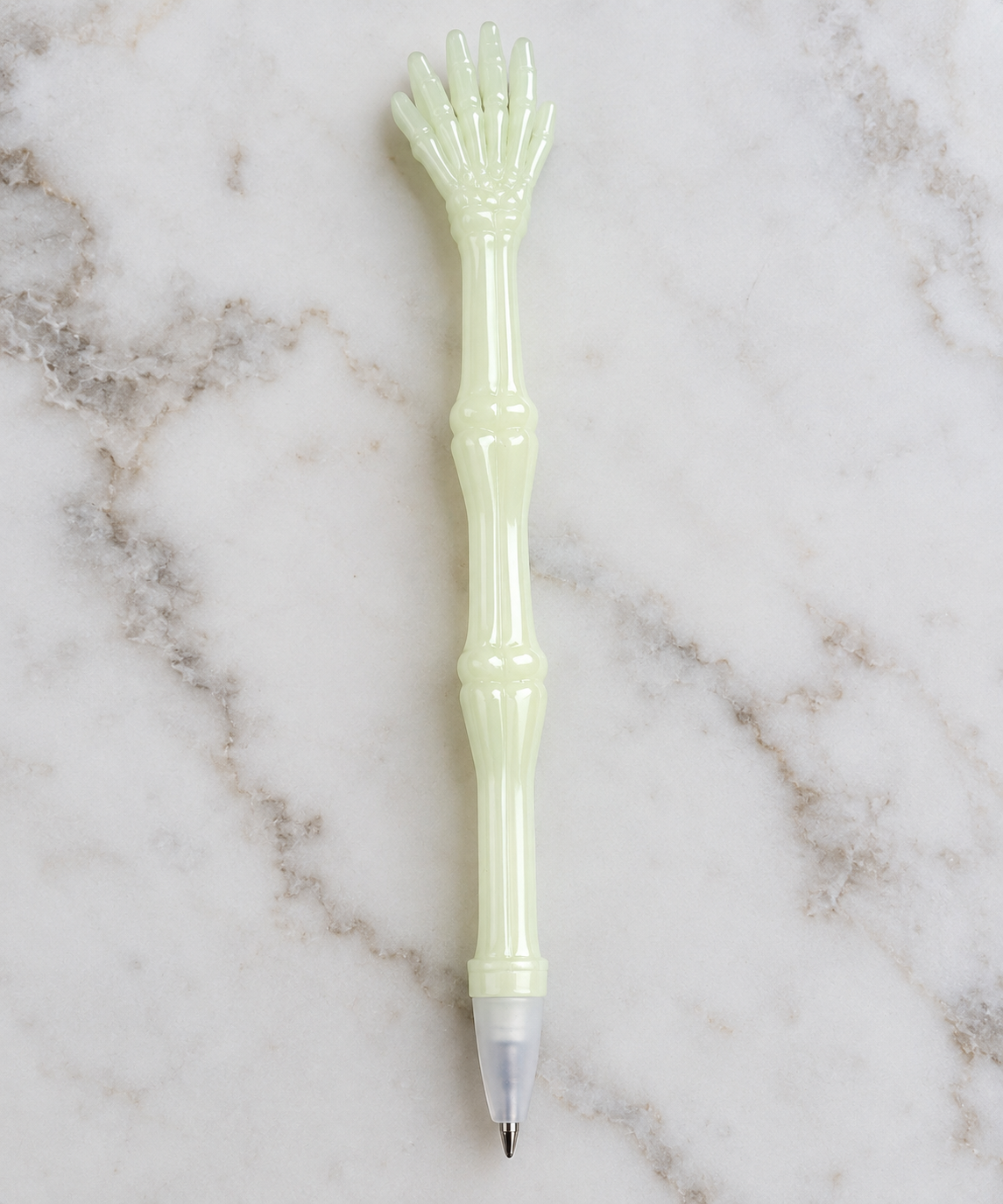 Glow-in-the-dark skeleton hand pen photographed on a light marble background