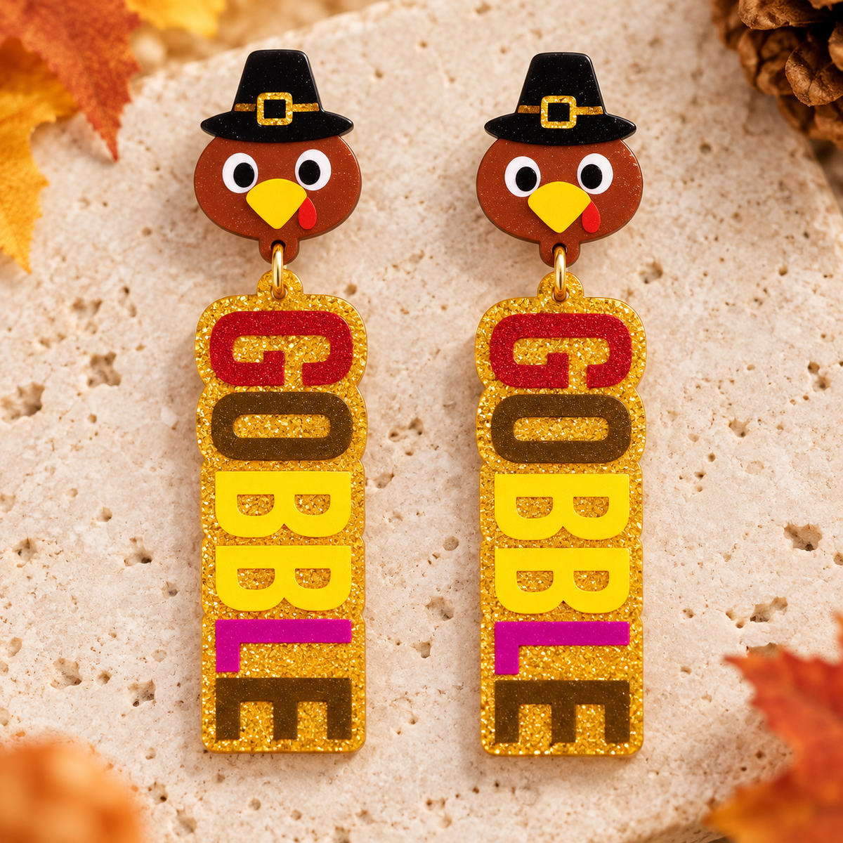 Close-up of Gobble turkey earrings showing glitter acrylic letters and pilgrim hat detail