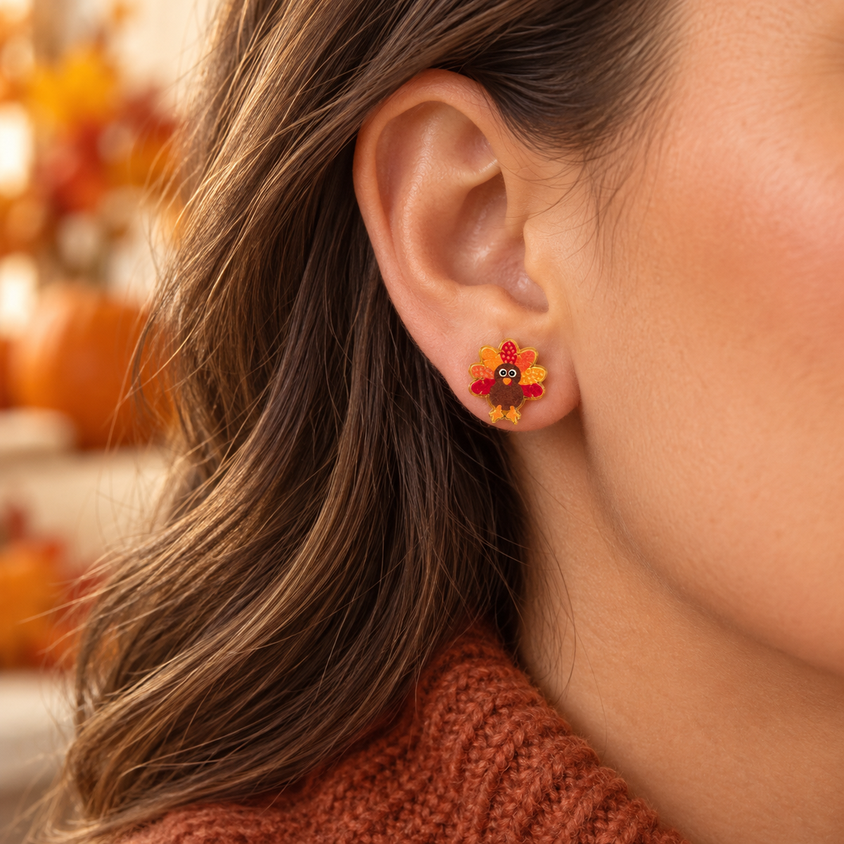 Close-up lifestyle image of little turkey Thanksgiving stud earring worn with a rust sweater