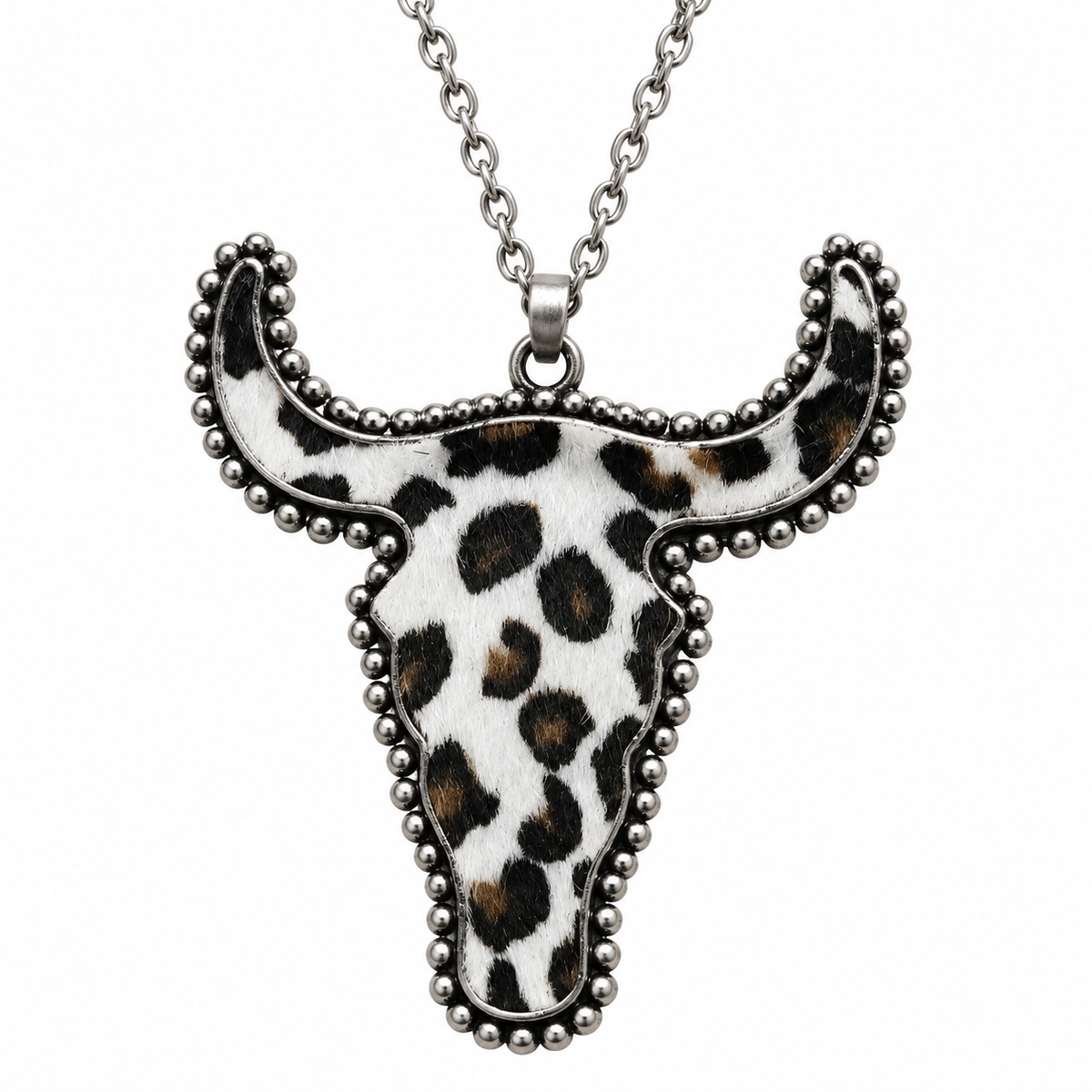 A silver-toned bull skull pendant necklace featuring a white hair-on-hide background with a black and brown leopard print pattern, set against a plain white background.