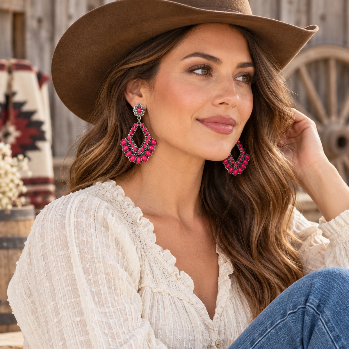 Woman wearing bright pink western statement earrings with cowboy hat and denim styling