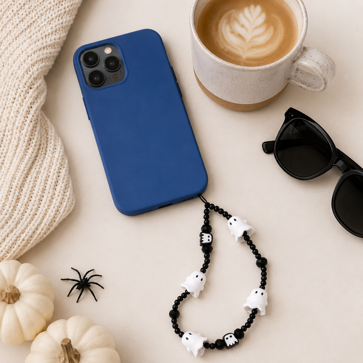 Emma holding the Boo Crew Ghost phone charm outdoors in a warm autumn setting with golden leaves