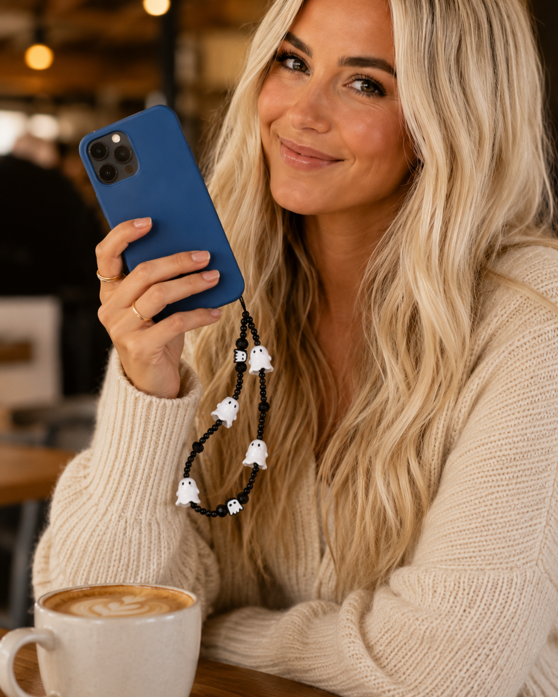Boo Crew Ghost phone charm styled in a fall flat lay with blue phone, latte, sunglasses, sweater and mini pumpkins