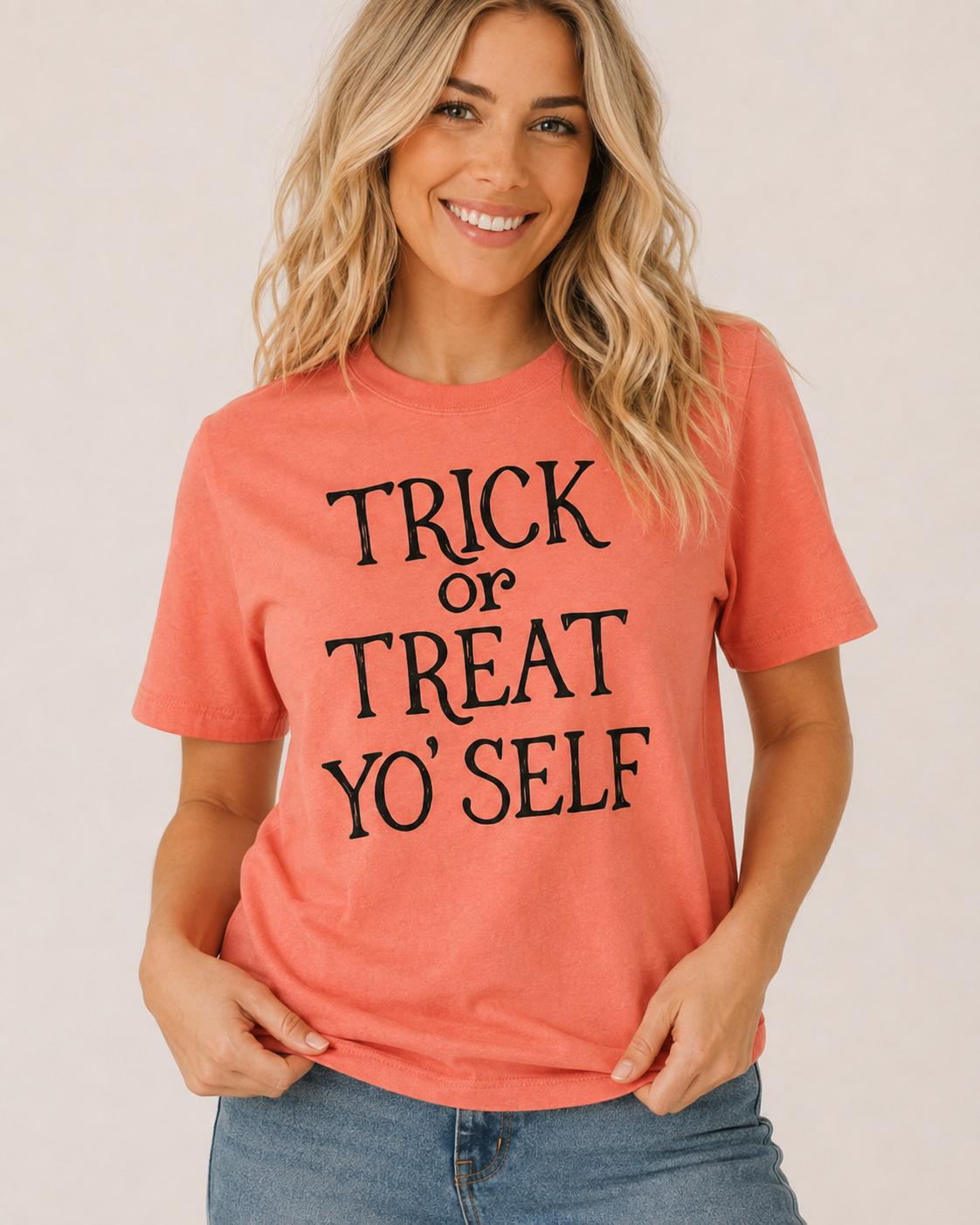 Close-up of Trick or Treat Yo’Self graphic showing black whimsical Halloween lettering on coral tee