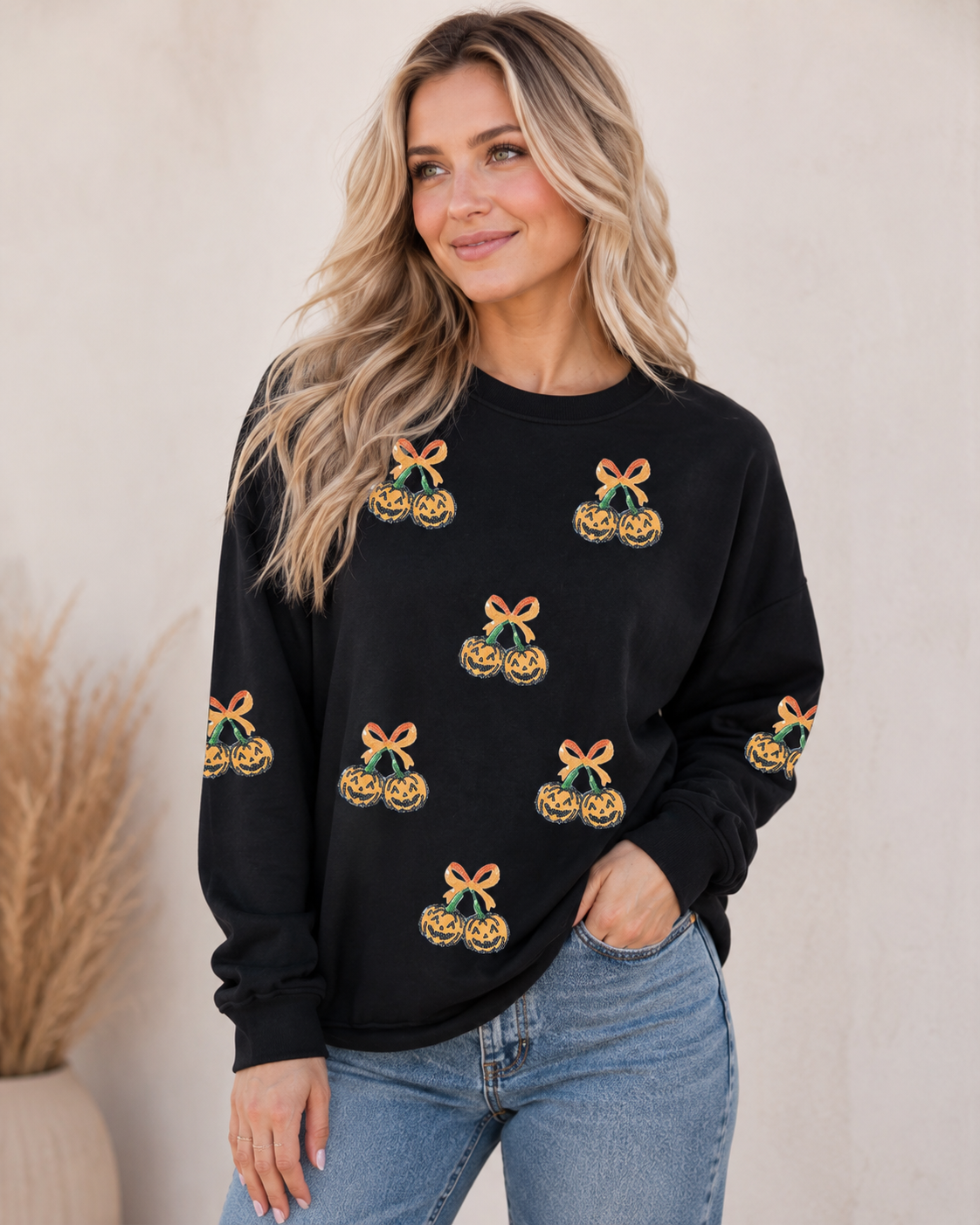Black Pumpkin Bow Sequin Sweatshirt with scattered orange pumpkin graphics styled with medium-wash denim.