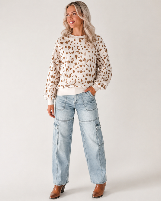 Blonde woman wearing the Prairie Fawn drop-shoulder sweatshirt with jeans and Western boots