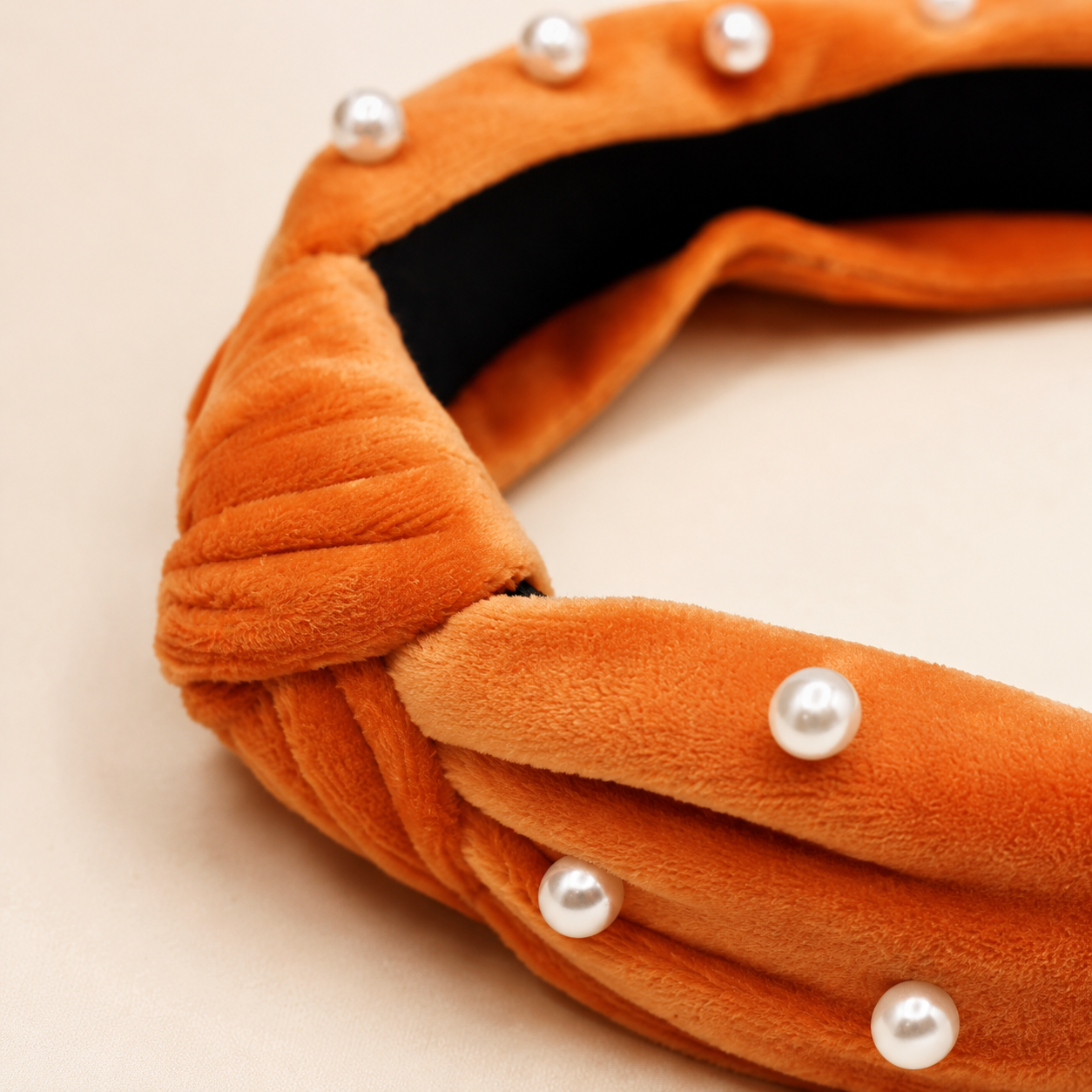 Close-up of burnt orange velvet knotted headband with faux pearl embellishments