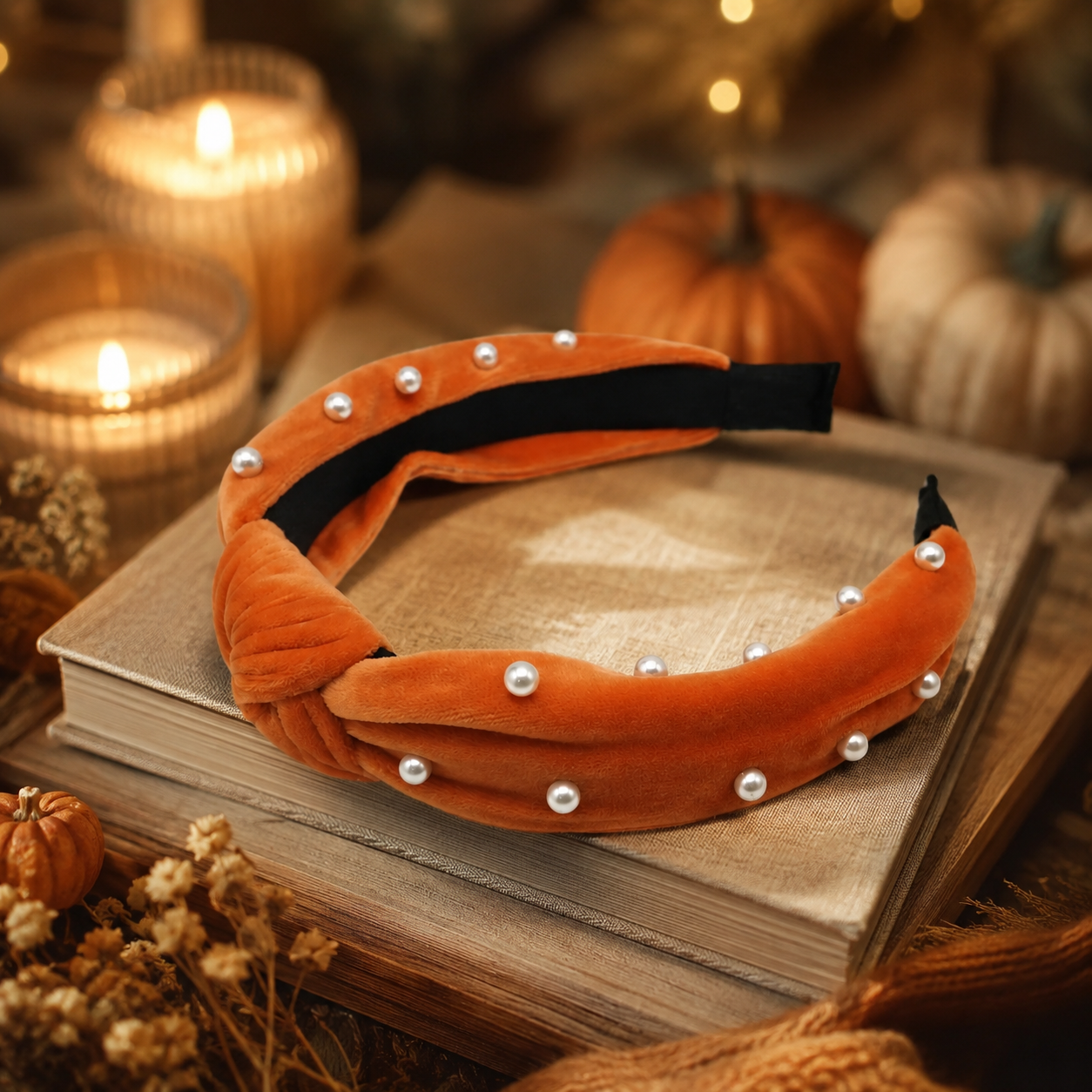 Burnt sienna pearl velvet headband styled on books with pumpkins and warm candlelight