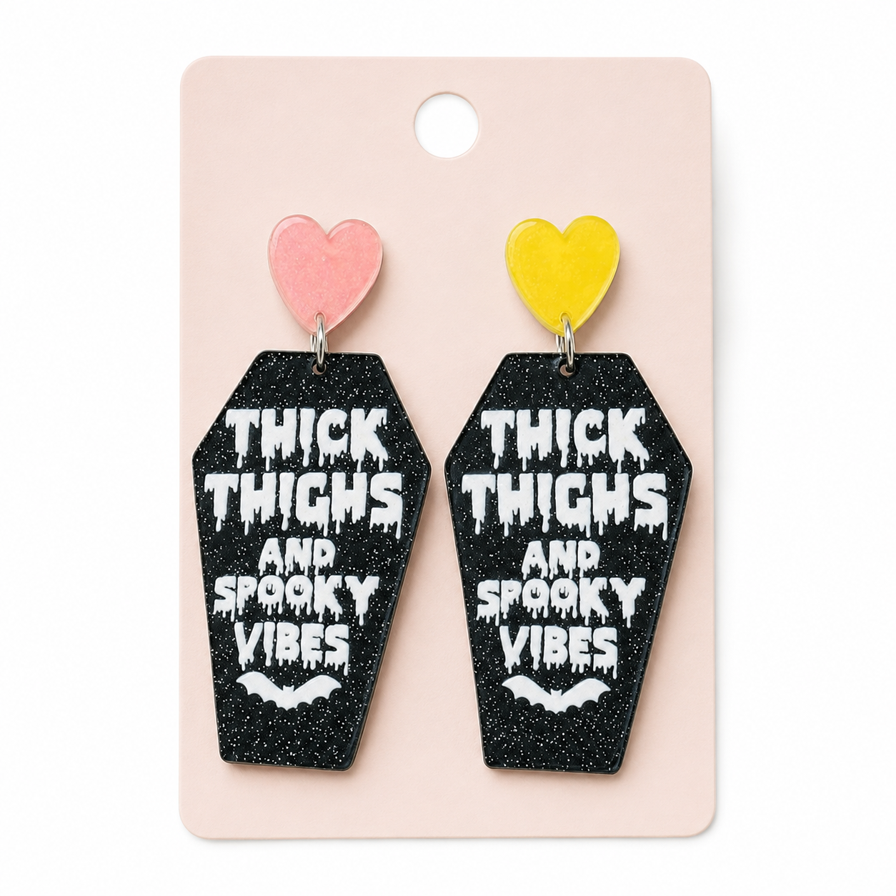 Thick Thighs & Spooky Vibes Coffin Earrings displayed on a blush jewelry card against a clean white background.