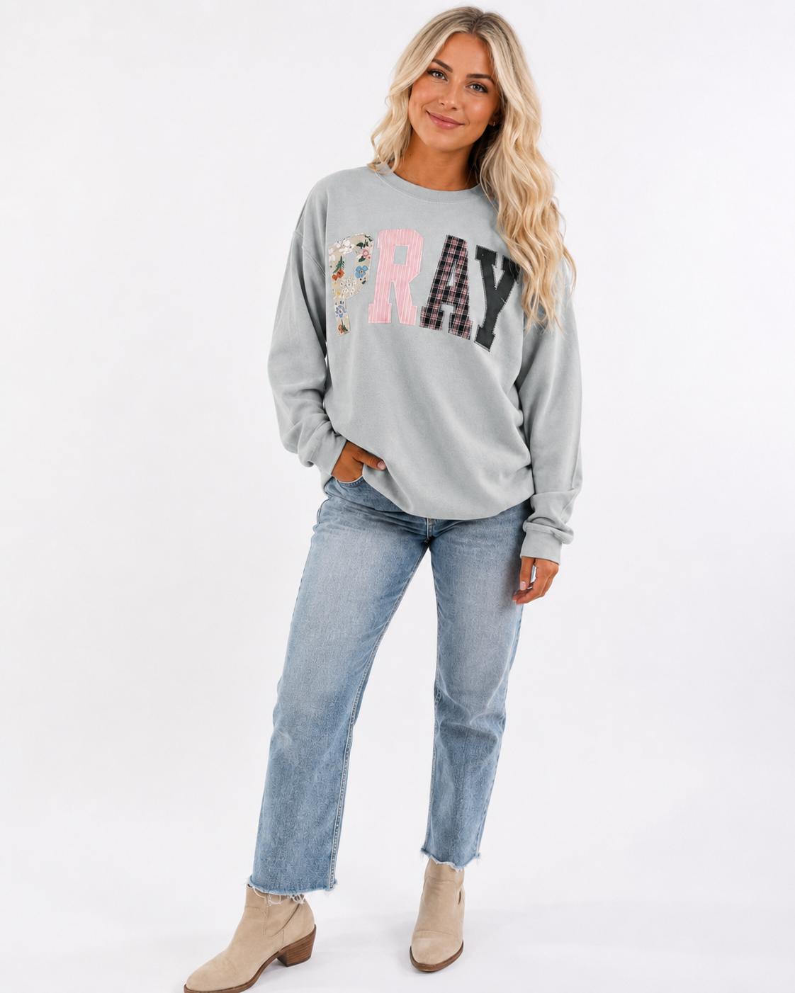 Pray Through It gray patchwork sweatshirt modeled by Emma on a clean white studio background.
