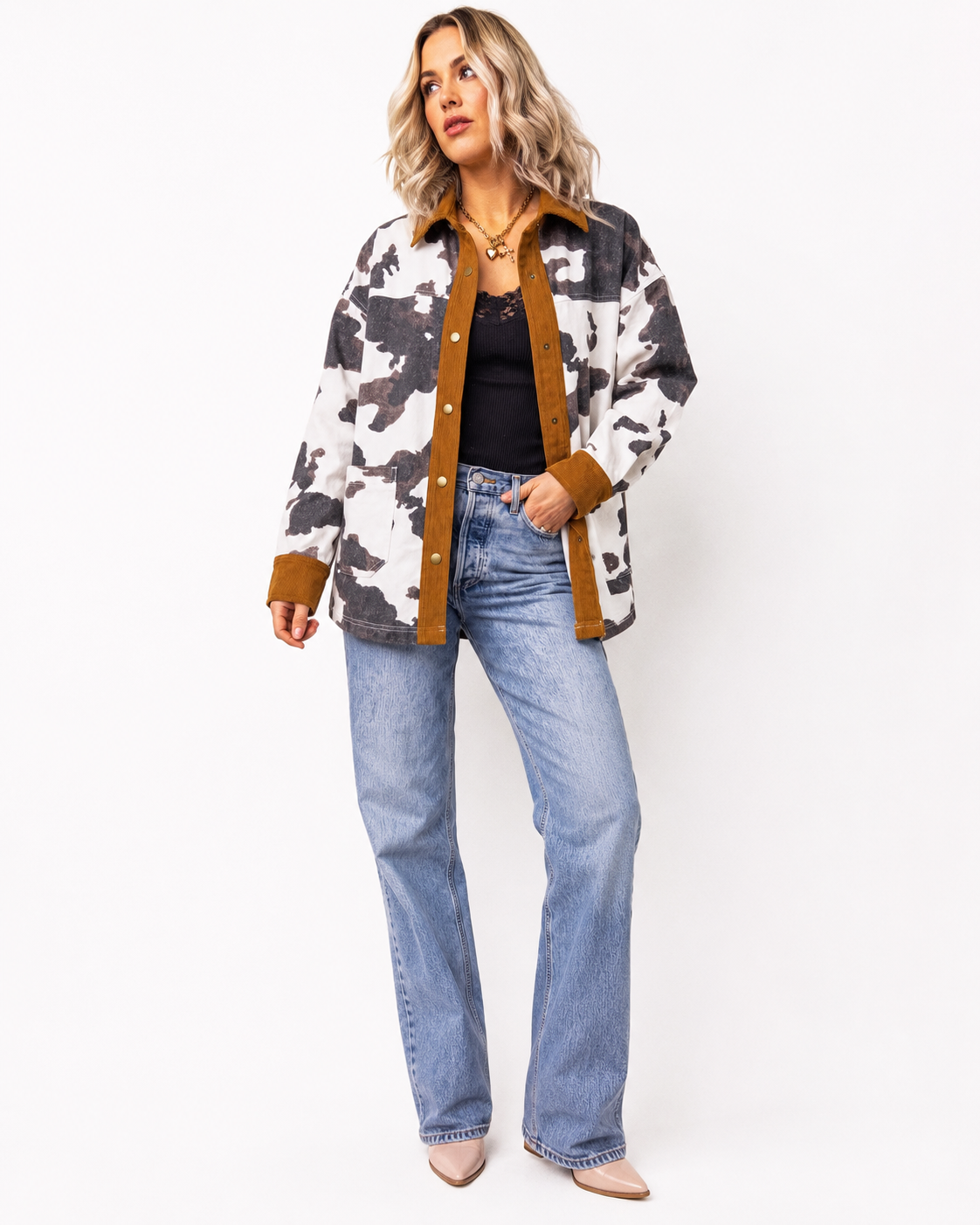 Emma modeling the Multicolour Western Cow Print Denim Jacket with a black lace-trim tank, light wash jeans and nude pointed-toe boots on a clean white studio background.