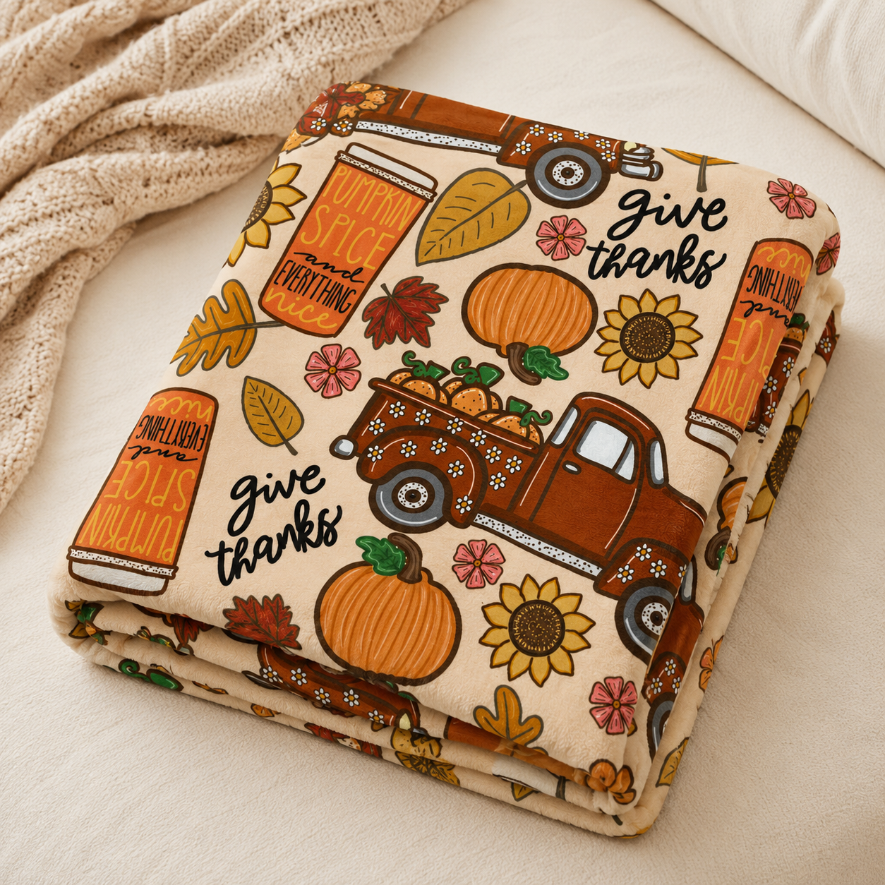 Fall throw blanket draped over a cream sofa with vintage trucks, pumpkins and pumpkin spice artwork