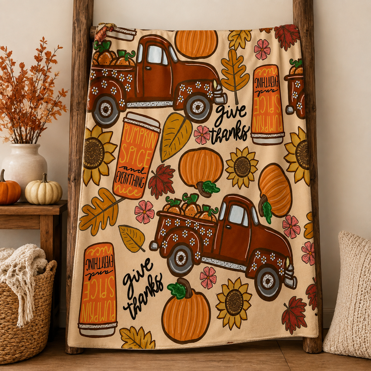 Fall throw blanket styled across a warm neutral bed with pumpkins, trucks, sunflowers and Give Thanks design